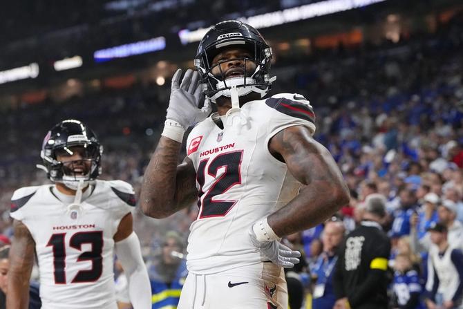 Houston Texans wide receiver Nico Collins holds his hand up to his ear in celebration.