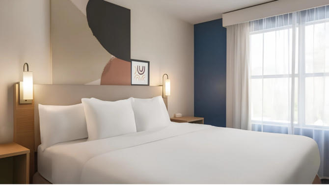 A pristine made bed in a sun-lit hotel room