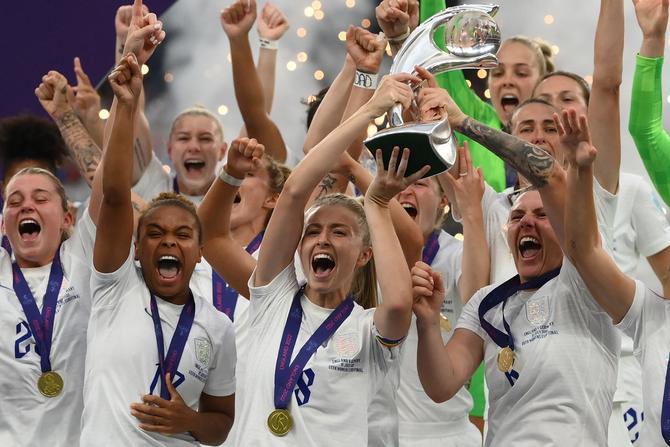England's midfielder Leah Williamson (C) and England's defender Millie Bright (R) lift the trophy as England's players celebrate after their win in the UEFA Women's Euro 2022 final football match between England and Germany at the Wembley stadium, in London, on July 31, 2022.