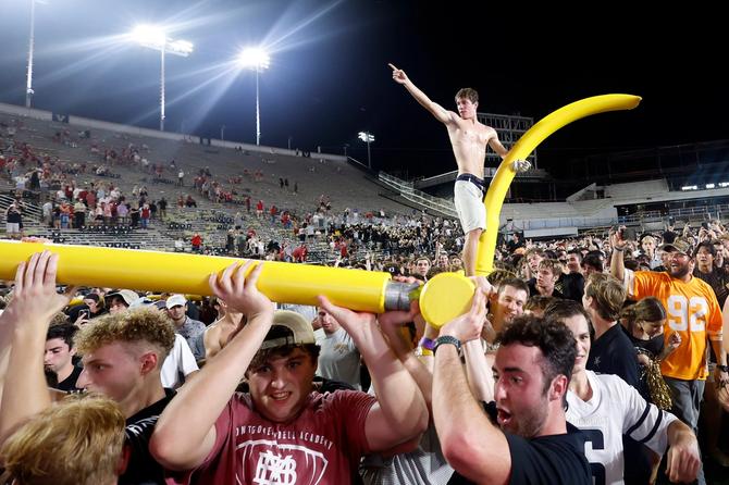Vanderbilt football fans carry one of their goal posts out of the stadium.