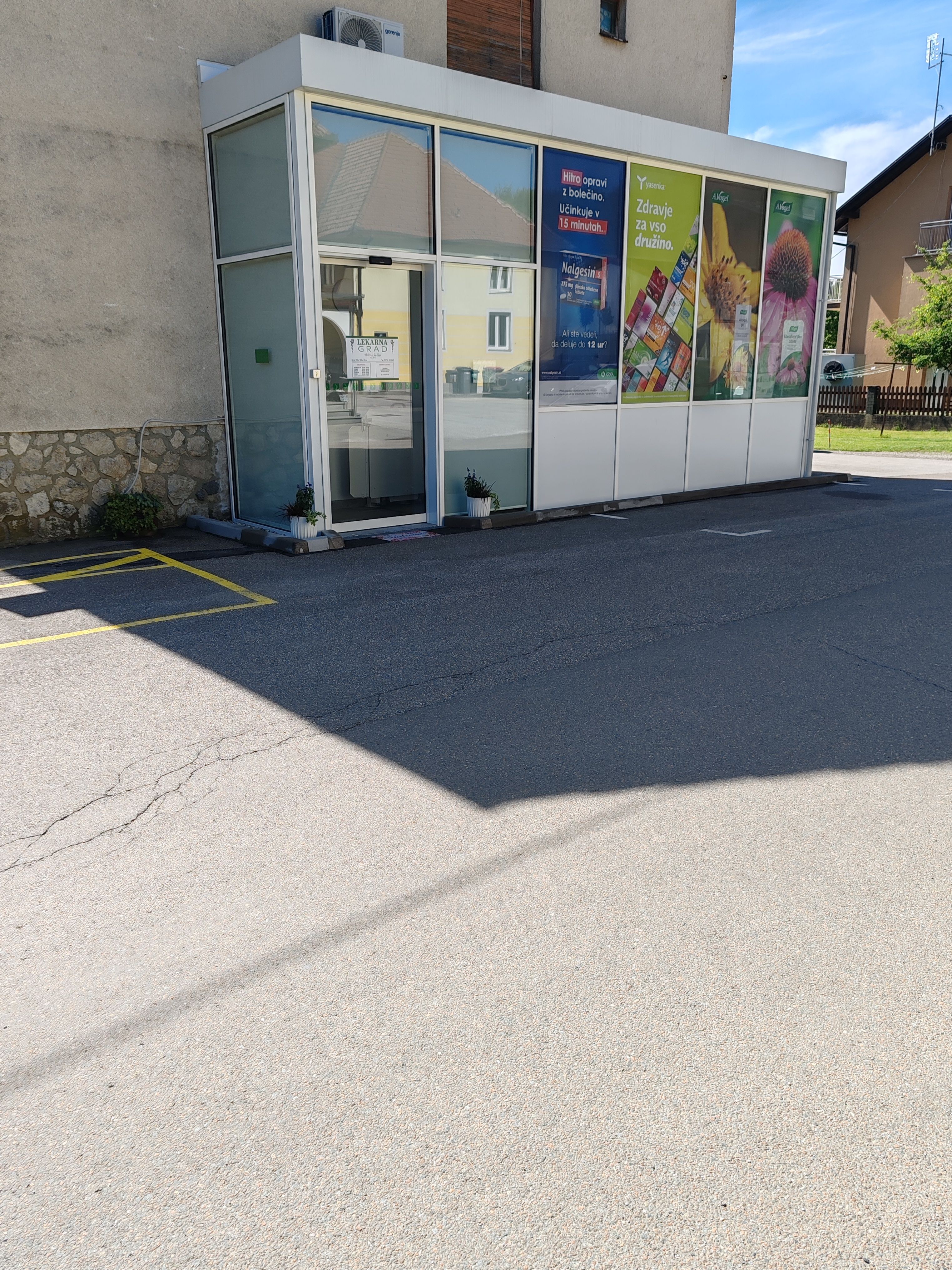 Lekarna Grad — širši pogled na zunanjost s parkiriščem in okolico
