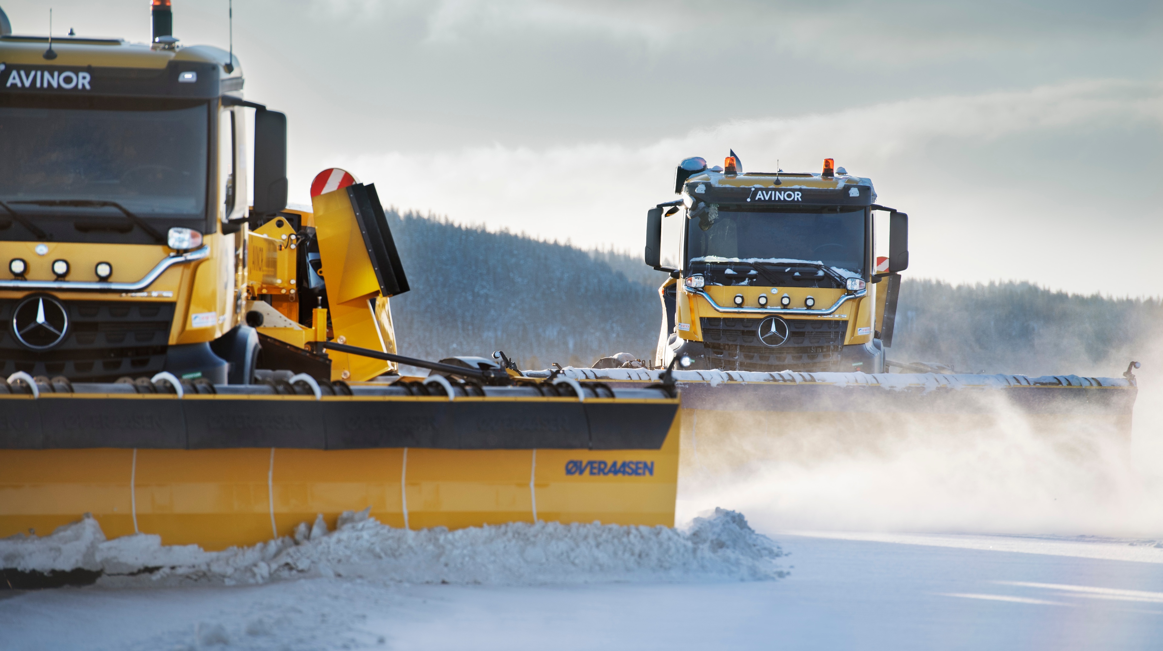 Close up og two yellow snowploughs ploughing snow at an airport runway