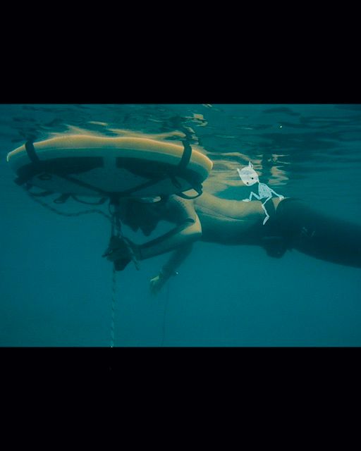  a freediver waiting on the surface to duckdive, with a small handdrawn character sitting on her back