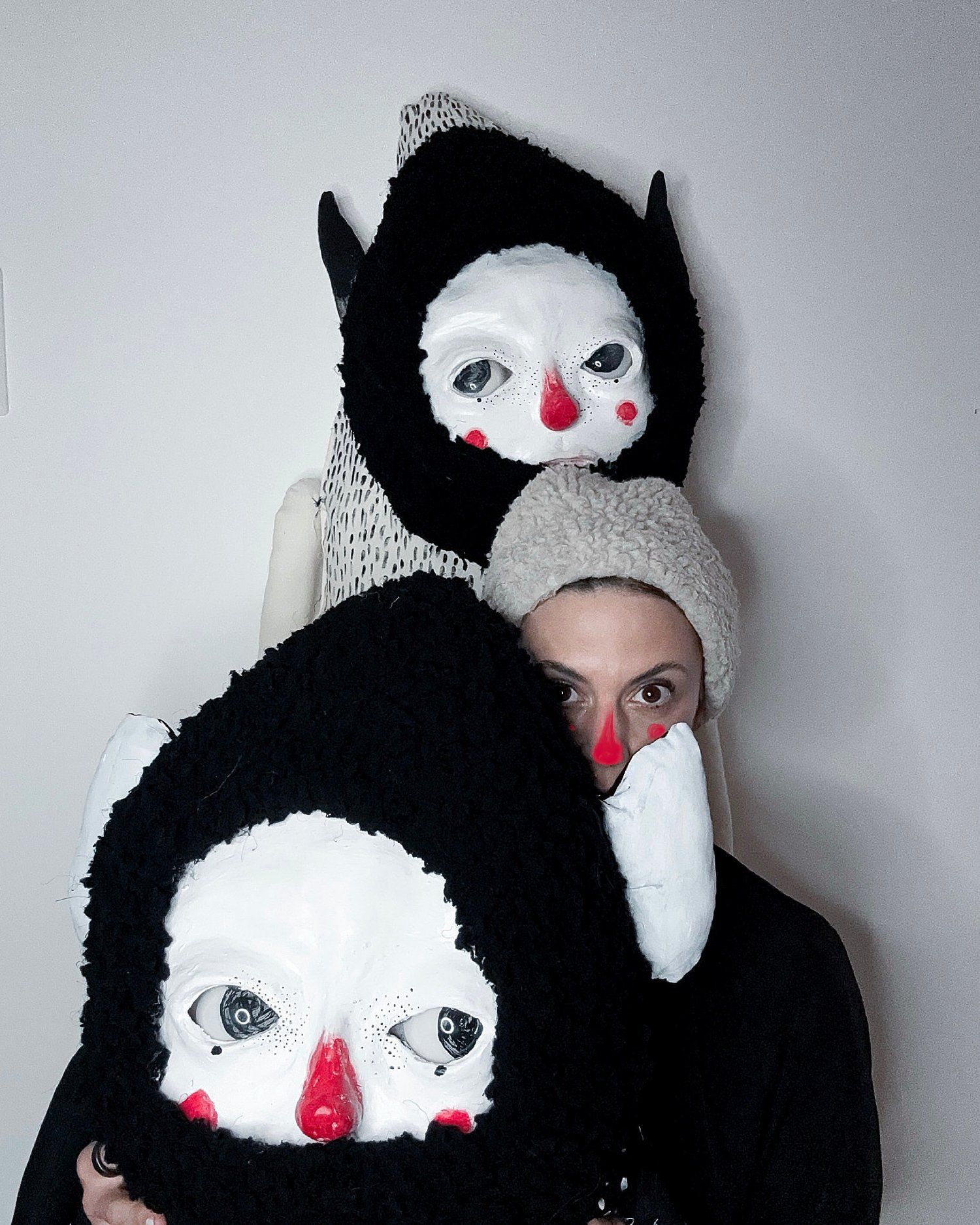 Portrait of artist Claudia Six with two large creature masks — part costume, part soft sculpture