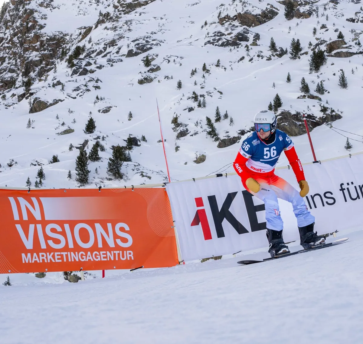 Crazy Curves / FIS Para Snowboard Worldcup: Para-Snowboarder mit Startnummer 56 auf der Rennpiste, davor die orange Bande der Marketingagentur Invisions