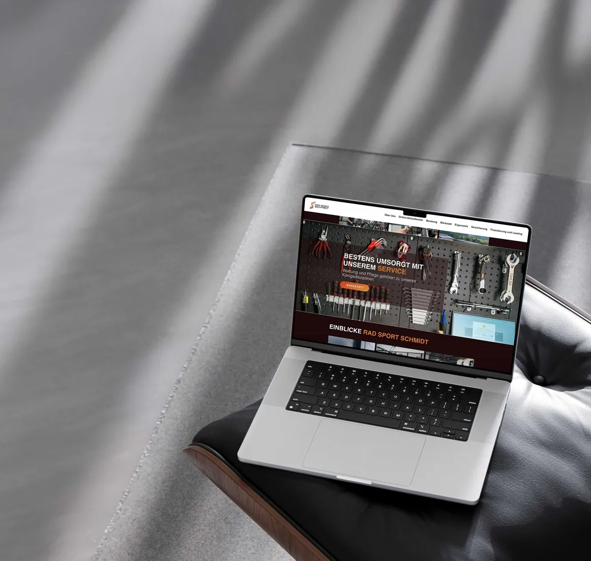 Rad Sport Schmidt: Aufgeklapptes MacBook im Streiflicht zeigt eine dunkel gestaltete Website mit Werkzeug- und Produktabbildungen