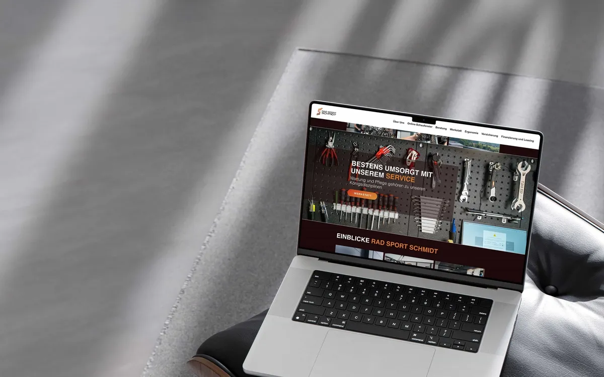 Rad Sport Schmidt: Aufgeklapptes MacBook im Streiflicht zeigt eine dunkel gestaltete Website mit Werkzeug- und Produktabbildungen