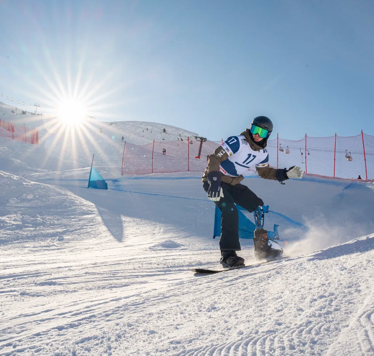 Crazy Curves / FIS Para Snowboard Worldcup: Para-Snowboarder im Gegenlicht auf einer präparierten Rennpiste, die Sonne steht tief über dem Grat