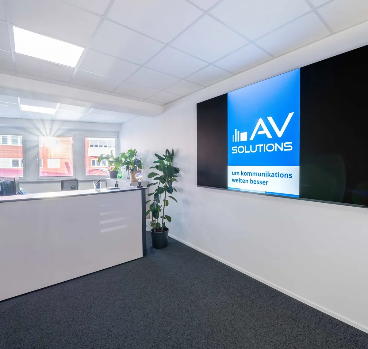 AVsolutions: Empfangsbereich eines Büros mit langer Bildschirmwand, auf der das Logo von AV Solutions läuft