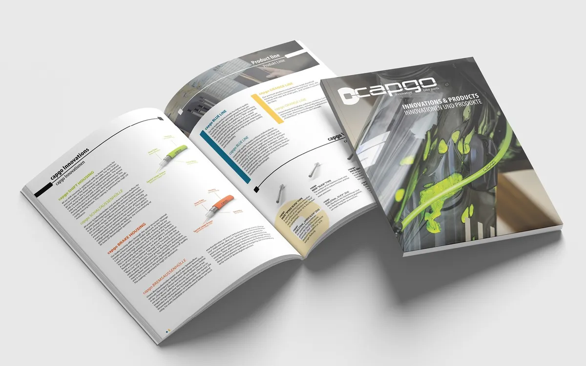 capgo: Aufgeschlagener capgo-Produktkatalog neben dem geschlossenen Titel mit grünem Zughüllen-Motiv