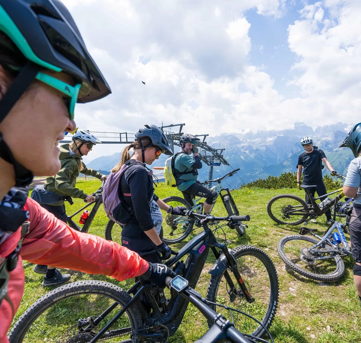 Bike Women Camp: Gruppe von Mountainbikerinnen mit Helmen auf einer Bergwiese, dahinter das Alpenpanorama