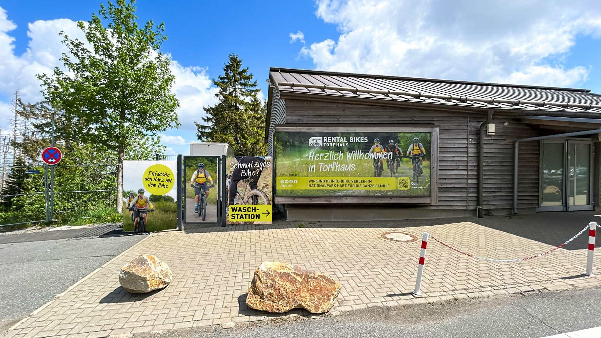 Rental Bikes Torfhaus: Die Verleihstation von Rental Bikes Torfhaus aus Holz mit Willkommensbanner und Waschstation