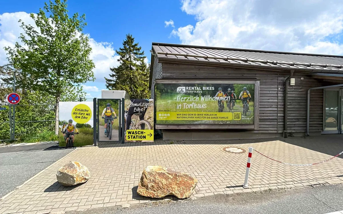 Rental Bikes Torfhaus: Die Verleihstation von Rental Bikes Torfhaus aus Holz mit Willkommensbanner und Waschstation