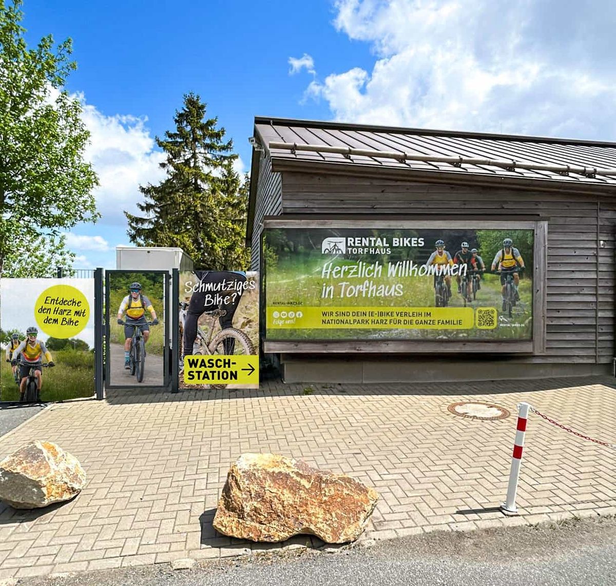Rental Bikes Torfhaus: Die Verleihstation von Rental Bikes Torfhaus aus Holz mit Willkommensbanner und Waschstation