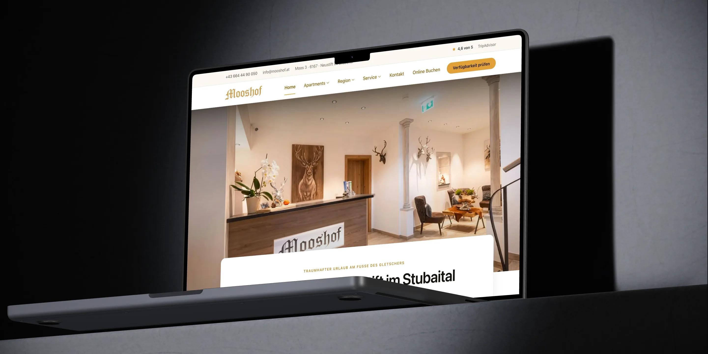 Webentwicklung: Ein MacBook Pro zeigt die Startseite von mooshof.at mit der Rezeption des Apartmenthauses.