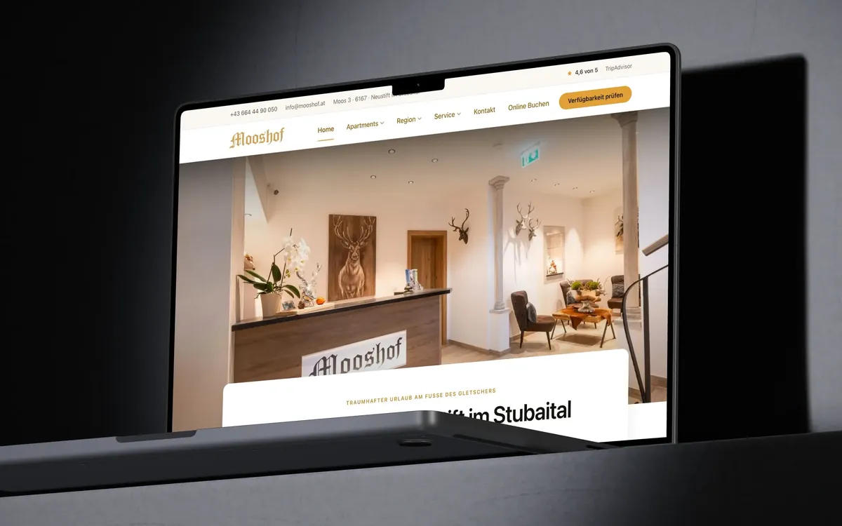 Webentwicklung: Ein MacBook Pro zeigt die Startseite von mooshof.at mit der Rezeption des Apartmenthauses.