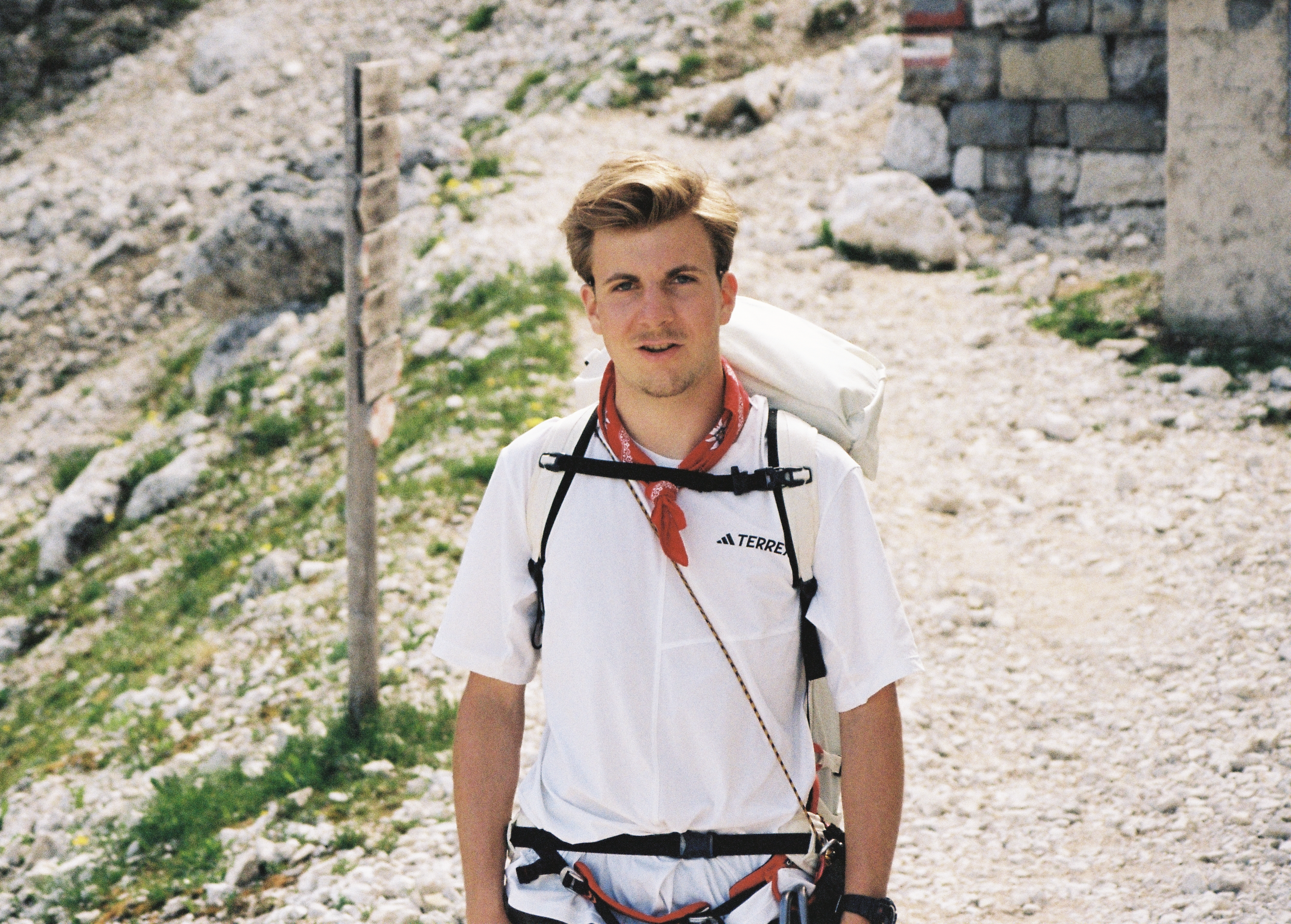Daniel Holst von Invisions auf einem Wanderweg in den Bergen, mit Rucksack und rotem Halstuch