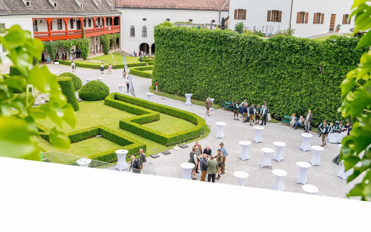 Inntal Catering: Blick von oben auf einen Barockgarten mit Hecken, Stehtischen und Gästen