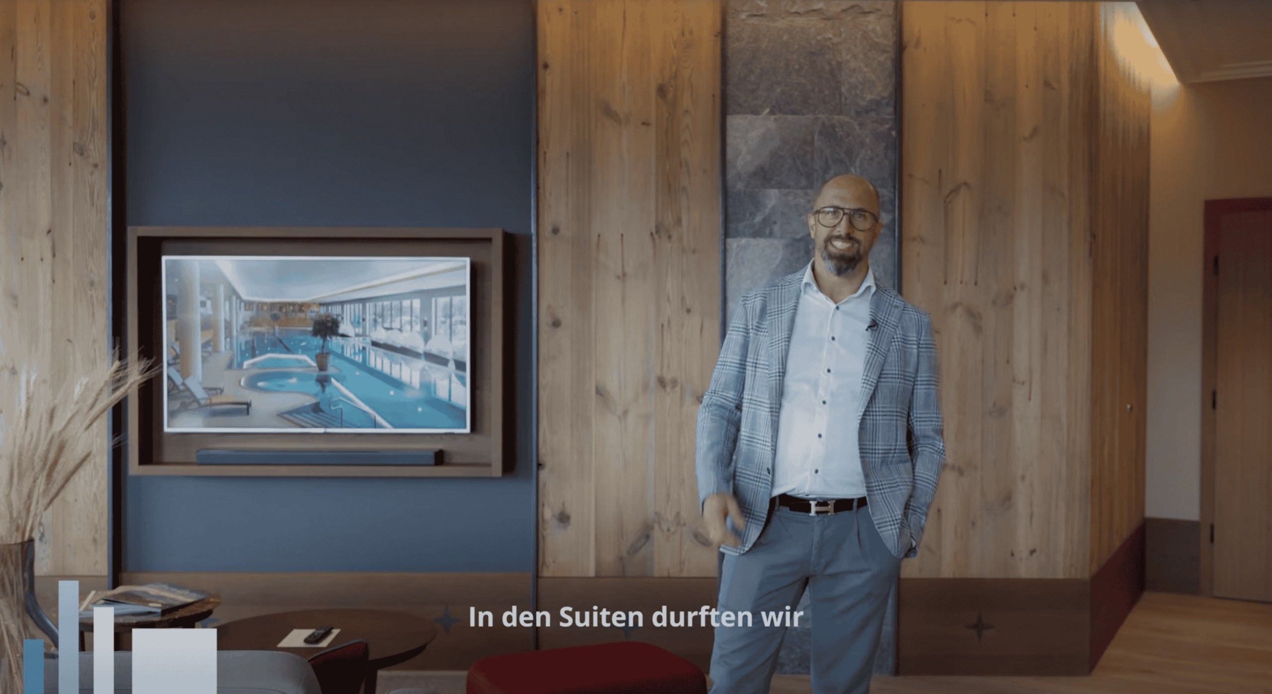 AVsolutions: Filmstill aus einem Imagefilm: ein Mann im Sakko steht in einem holzvertäfelten Hotelflur