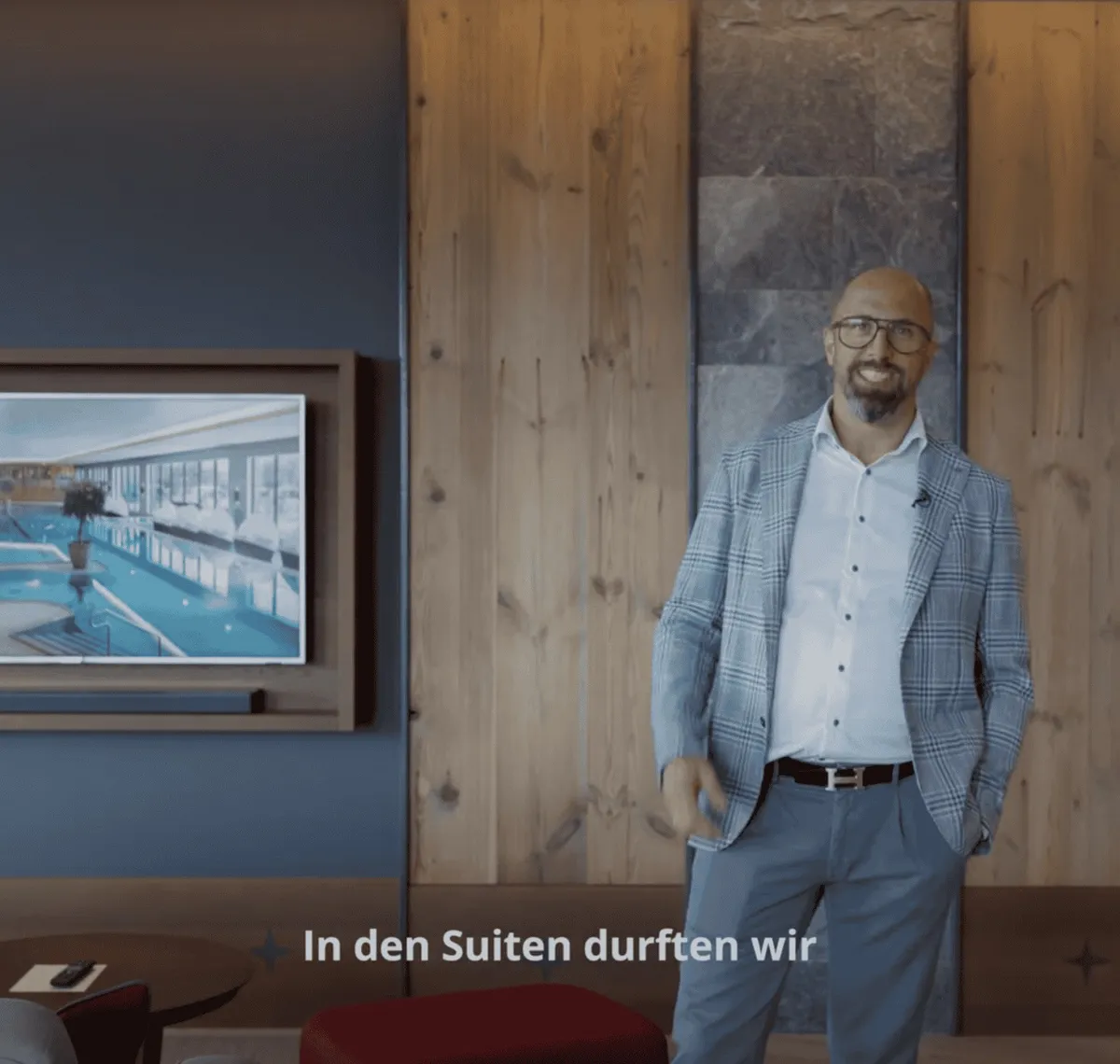 AVsolutions: Filmstill aus einem Imagefilm: ein Mann im Sakko steht in einem holzvertäfelten Hotelflur