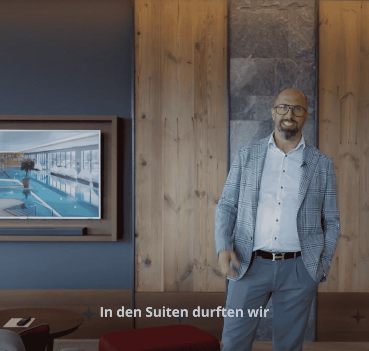 AVsolutions: Filmstill aus einem Imagefilm: ein Mann im Sakko steht in einem holzvertäfelten Hotelflur