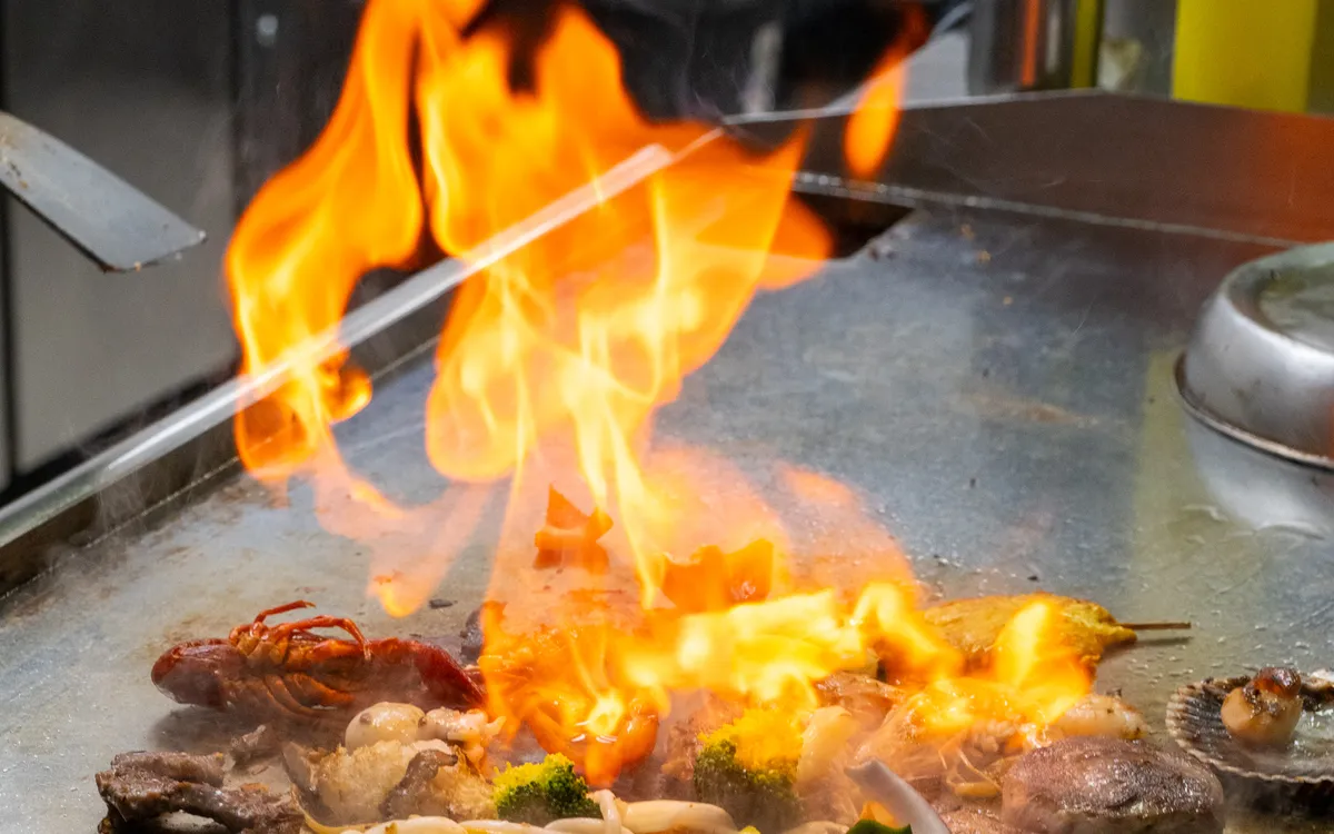 Reels für Buffet und Grill: Eine hohe Flamme über der Teppanyaki-Platte, davor Gemüse und Meeresfrüchte auf der heissen Fläche.