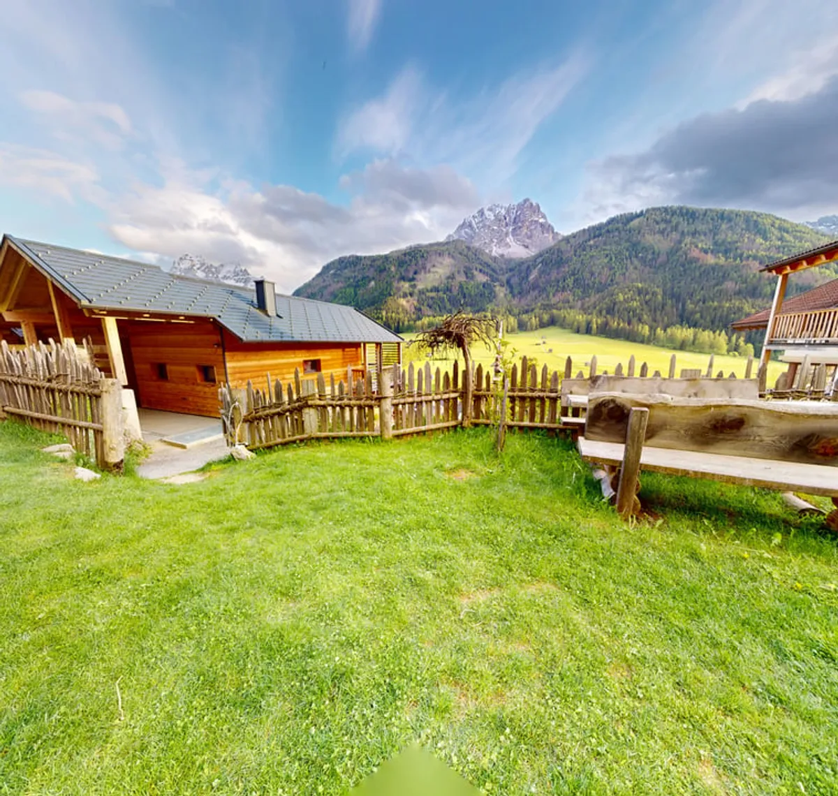 Stabinger Hof: Die Holzchalets des Stabinger Hofs auf einer Bergwiese vor den Dolomiten