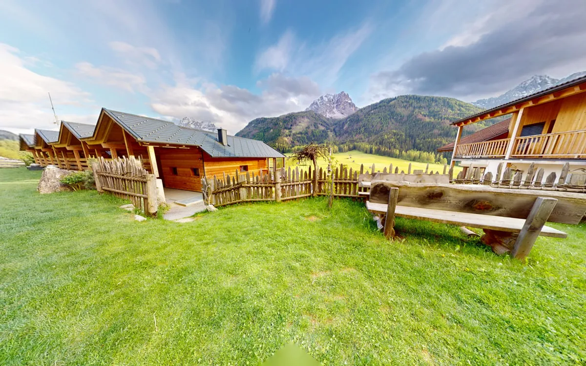 Matterport-Rundgang: Die Holzchalets des Stabinger Hofs auf einer Bergwiese vor den Dolomiten