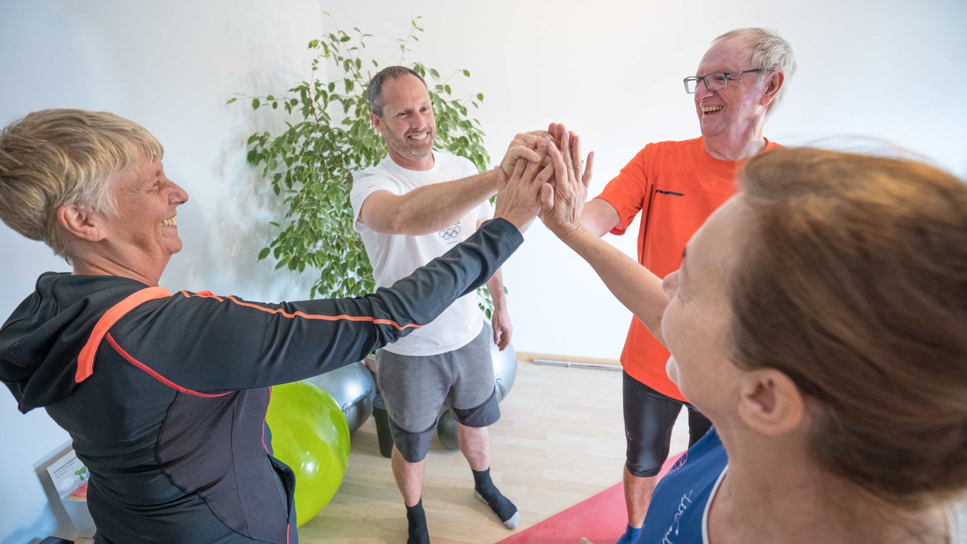 Robert Treitinger: Vier Personen klatschen sich nach einer Trainingseinheit im Gymnastikraum ab