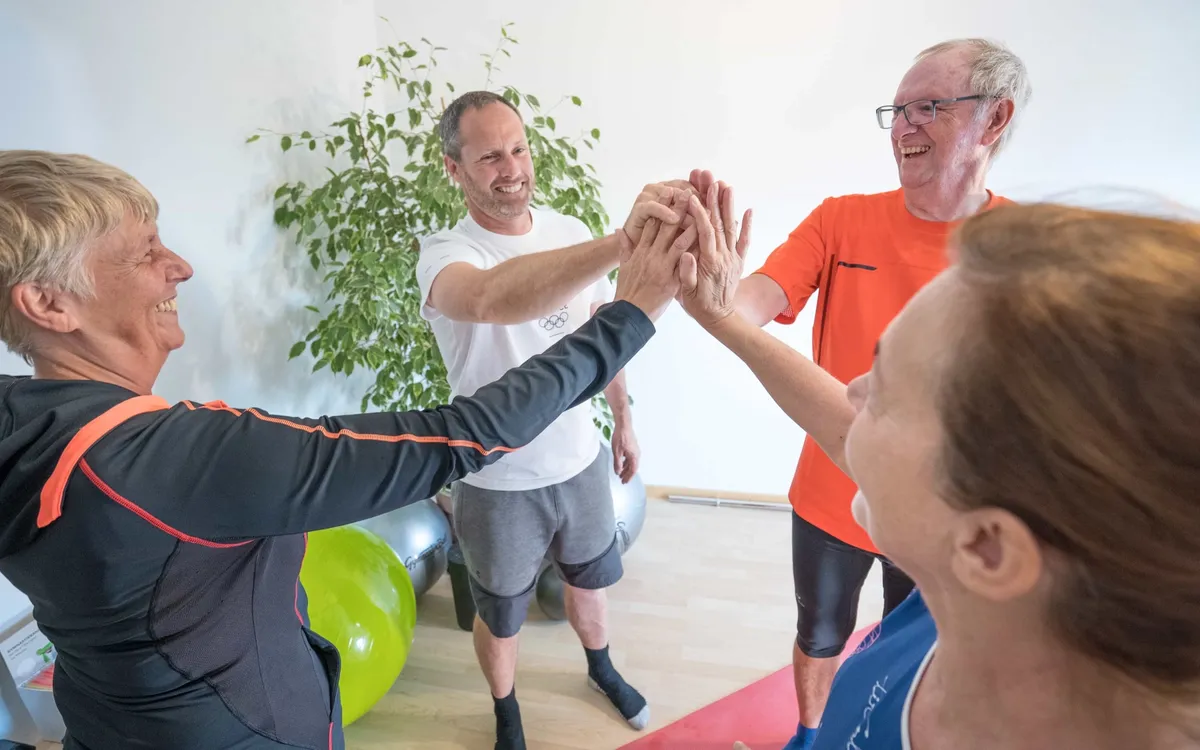Robert Treitinger: Vier Personen klatschen sich nach einer Trainingseinheit im Gymnastikraum ab