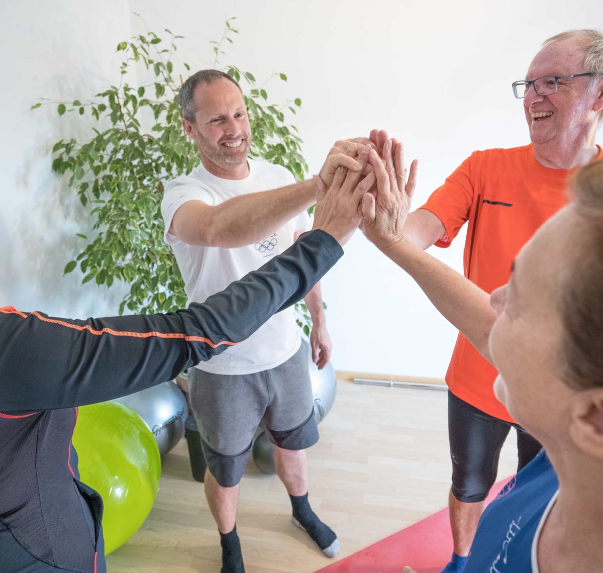 Robert Treitinger: Vier Personen klatschen sich nach einer Trainingseinheit im Gymnastikraum ab