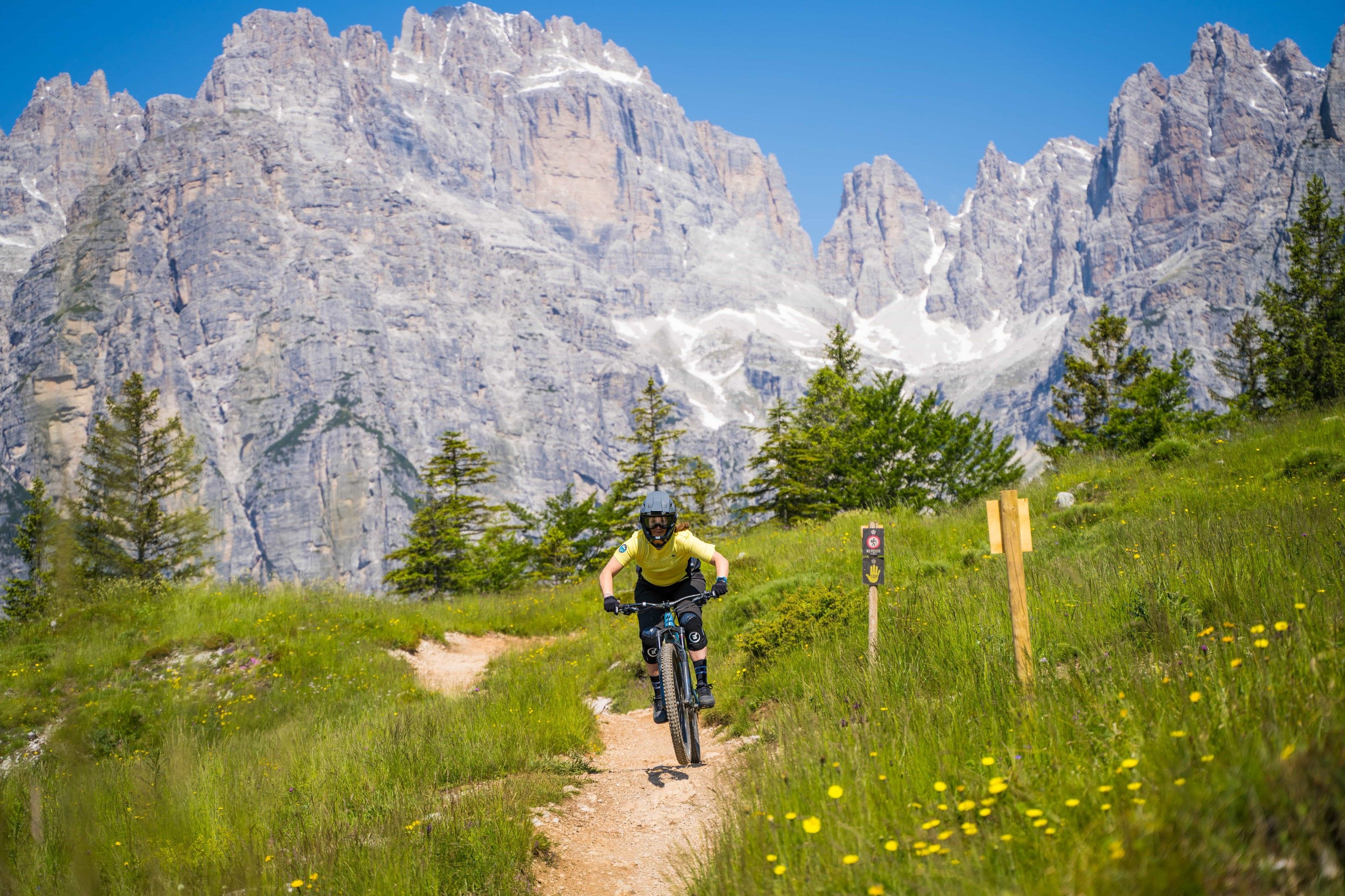 Bike Women Camp: Mountainbiker auf einem Wiesentrail vor der Felswand der Dolomiten