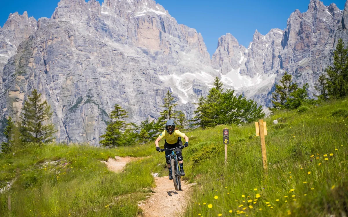 Bike Women Camp: Mountainbiker auf einem Wiesentrail vor der Felswand der Dolomiten