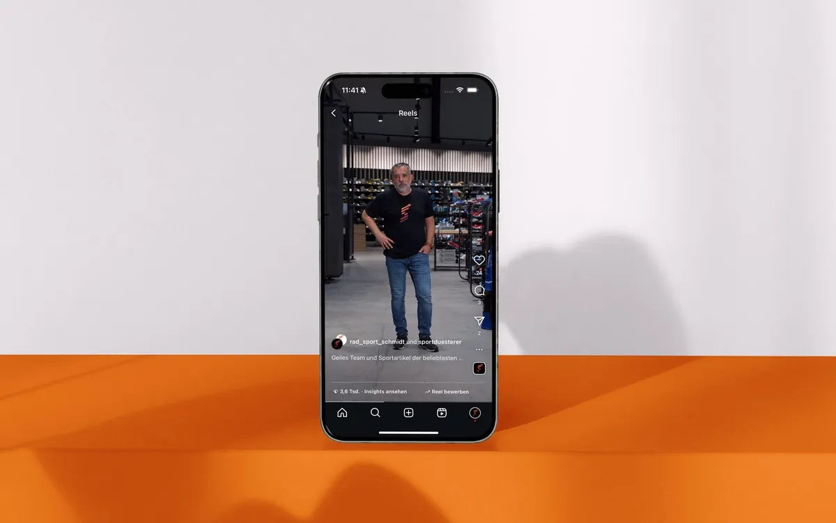Employer Branding Reels: Smartphone über orangem Sockel zeigt ein Recruiting-Reel mit einem Mitarbeiter im Verkaufsraum