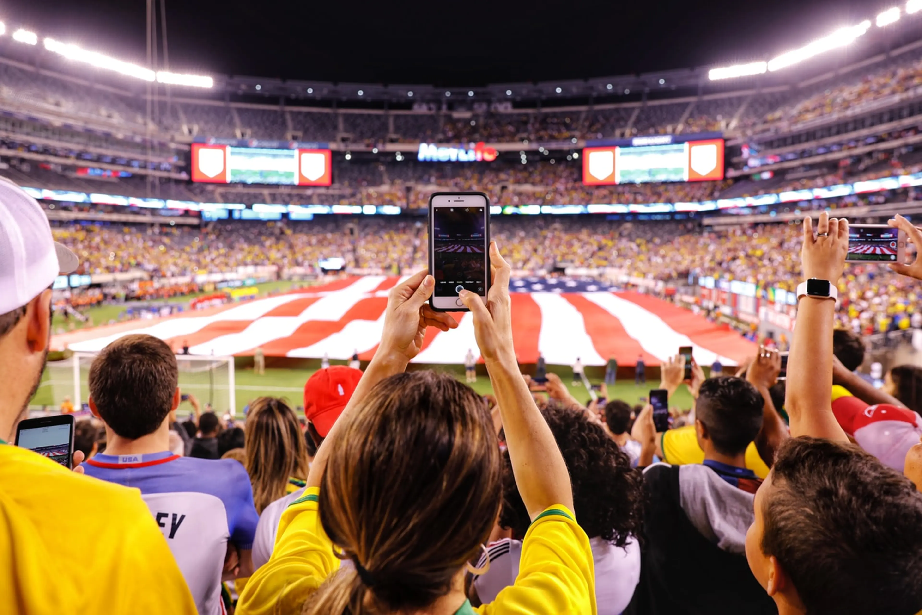 Fans at a stadium taking live streaming the action on their phones