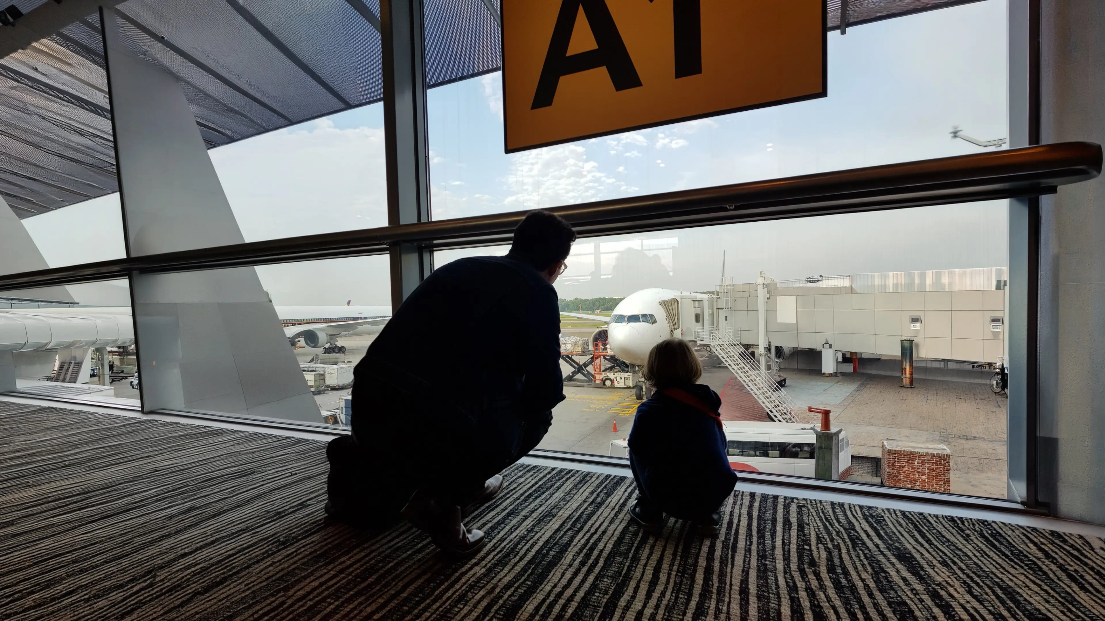 Man and a child looking at a commercial plane in an airport