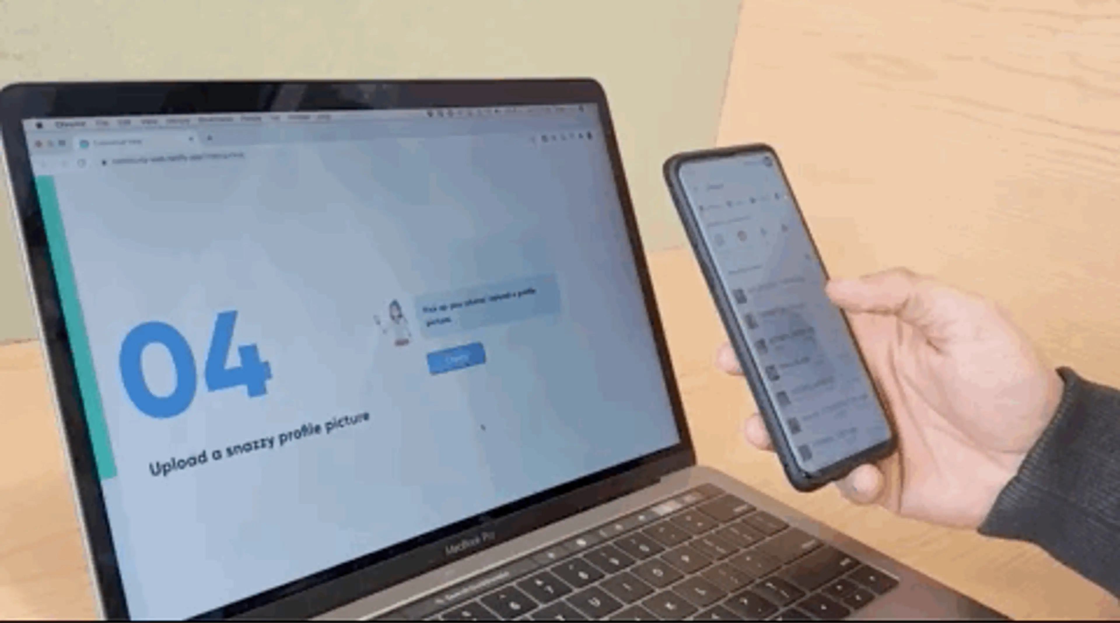 Person using a mobile phone next to a laptop