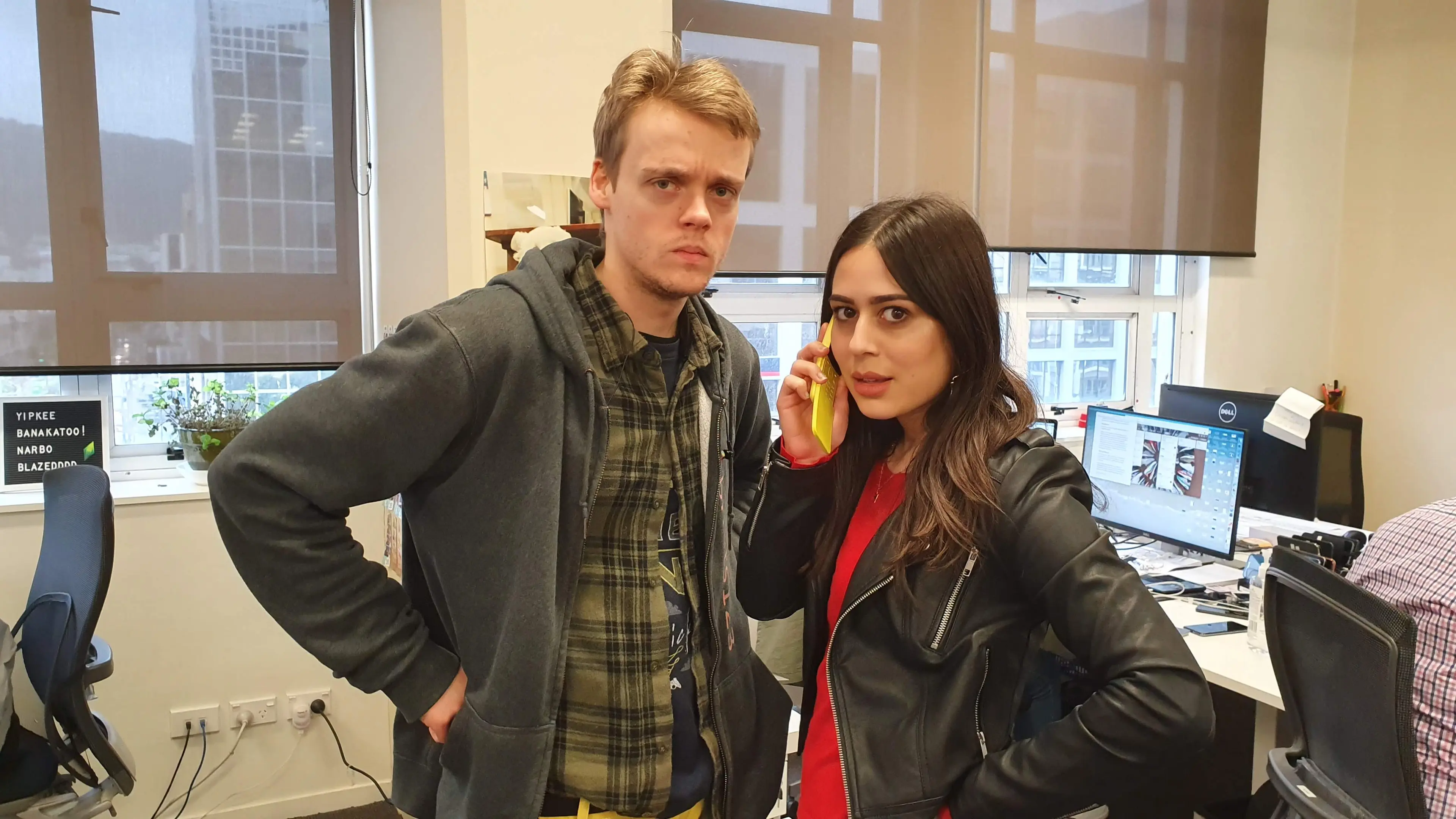 A man standing next to  woman on a low-spec mobile phone