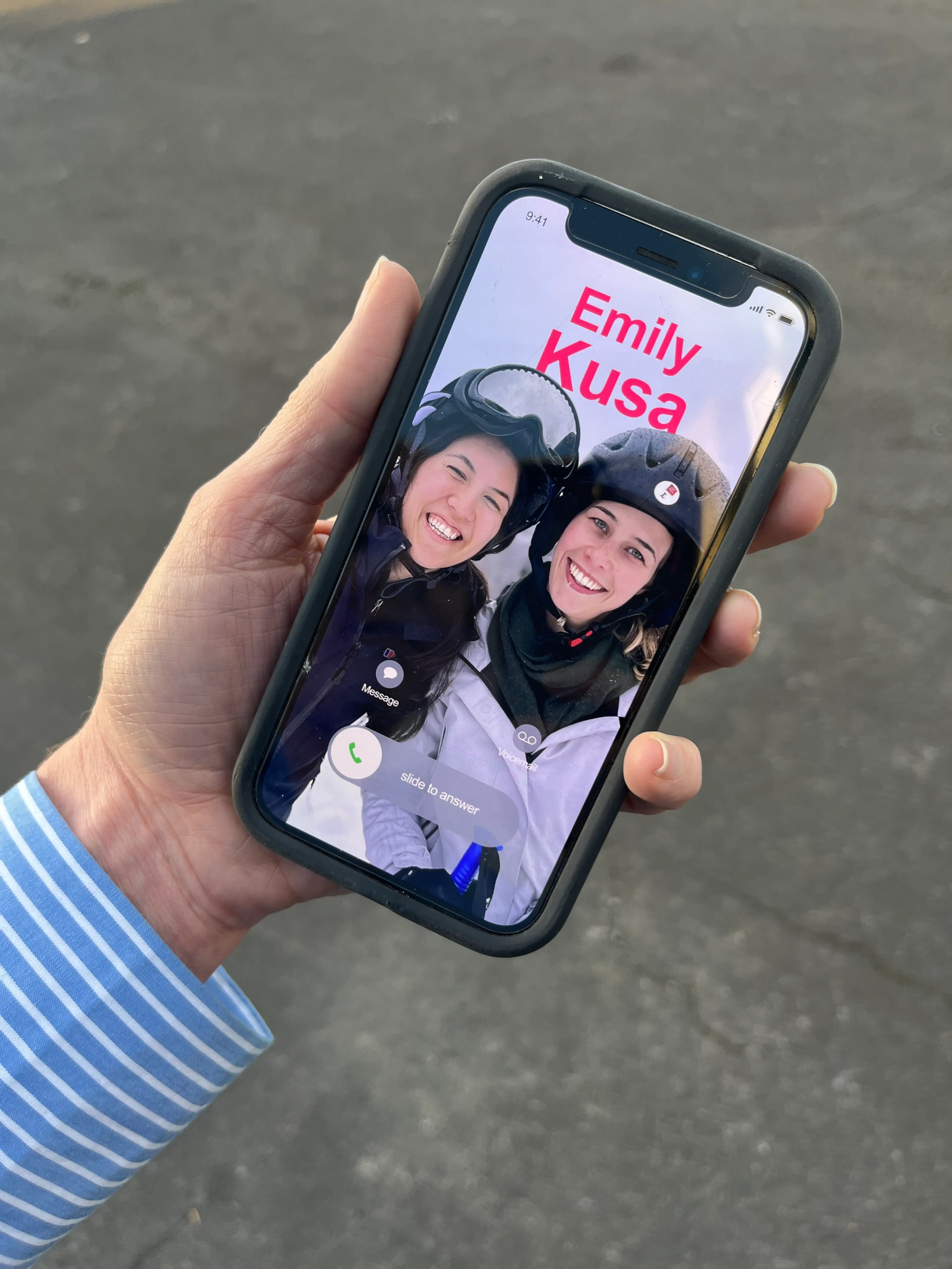Hand holding an iPhone while making a video call to two females