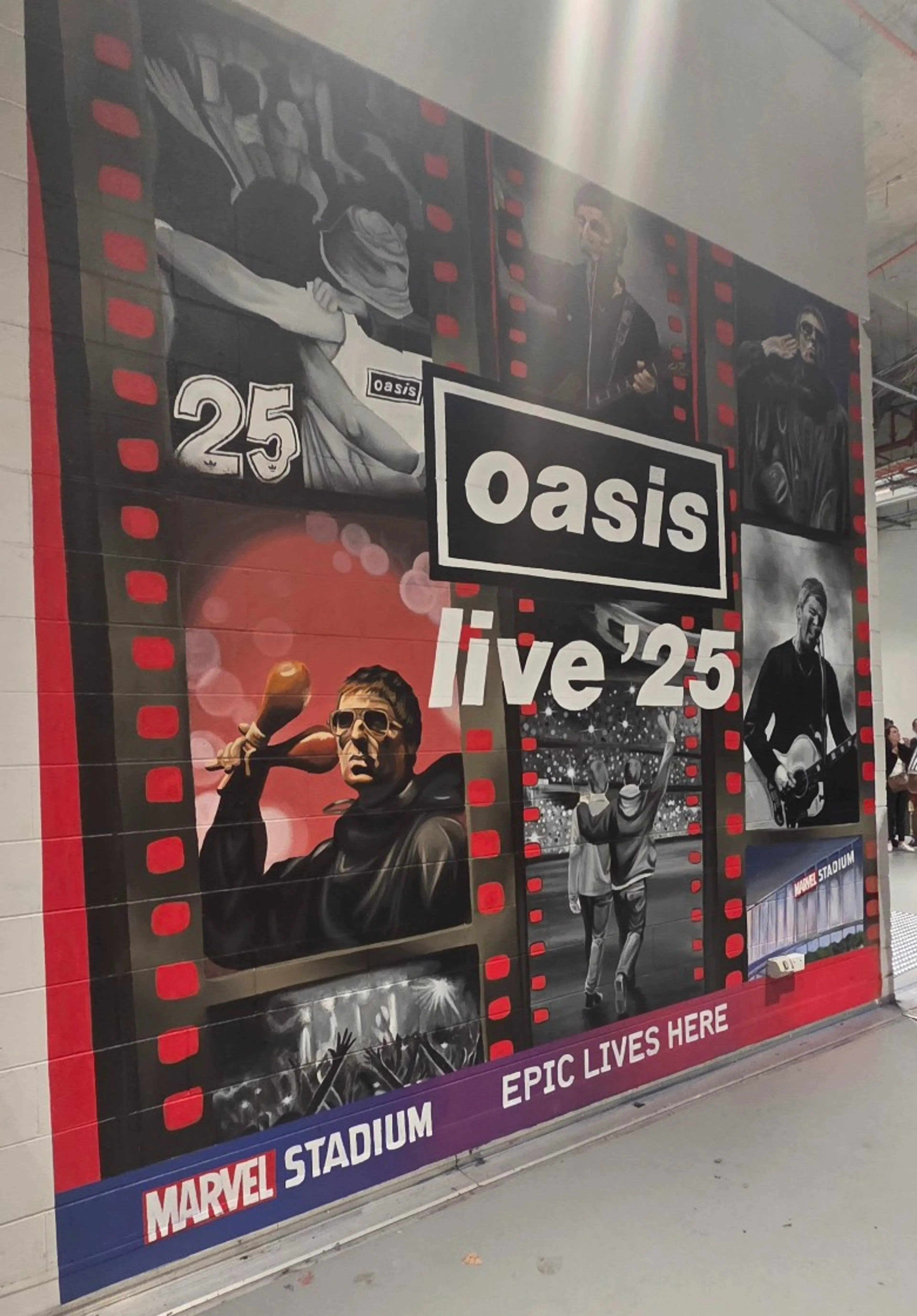 Large painted mural inside Marvel Stadium featuring band imagery and performance scenes, with “oasis live ’25” written in the centre.