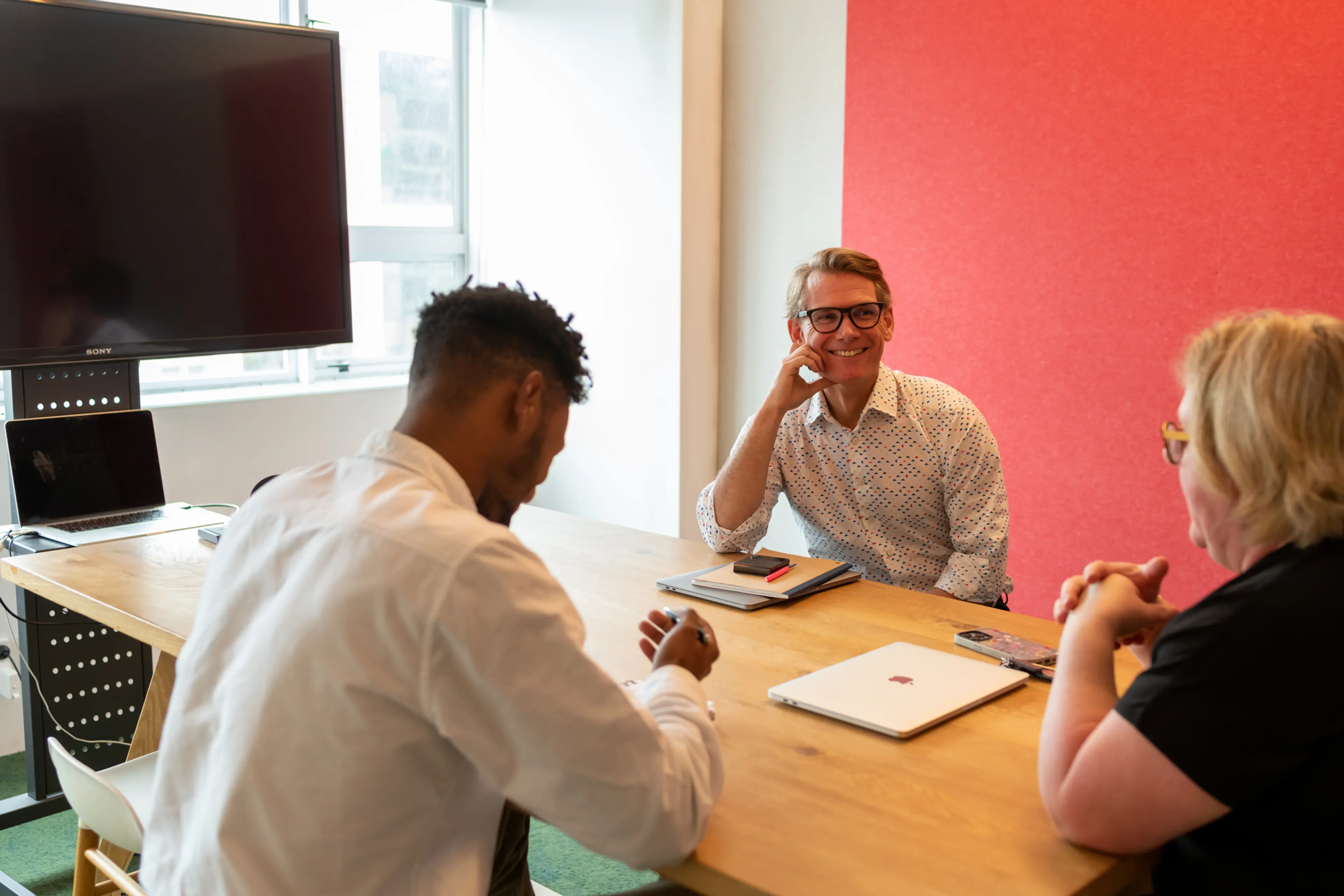 Three people sitting at a table in a meeting room