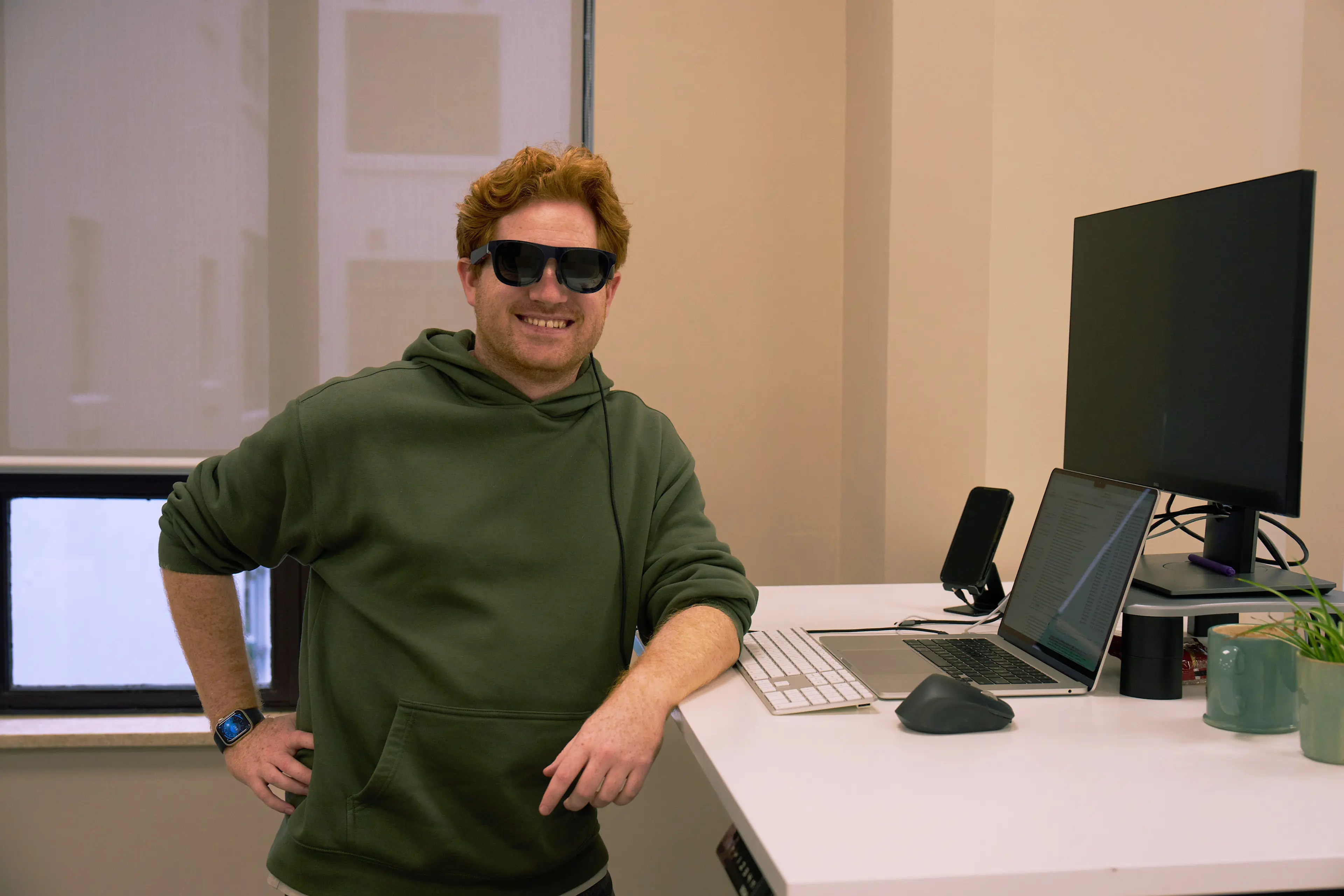Adam is wearing AR glasses in front of a laptop and monitor