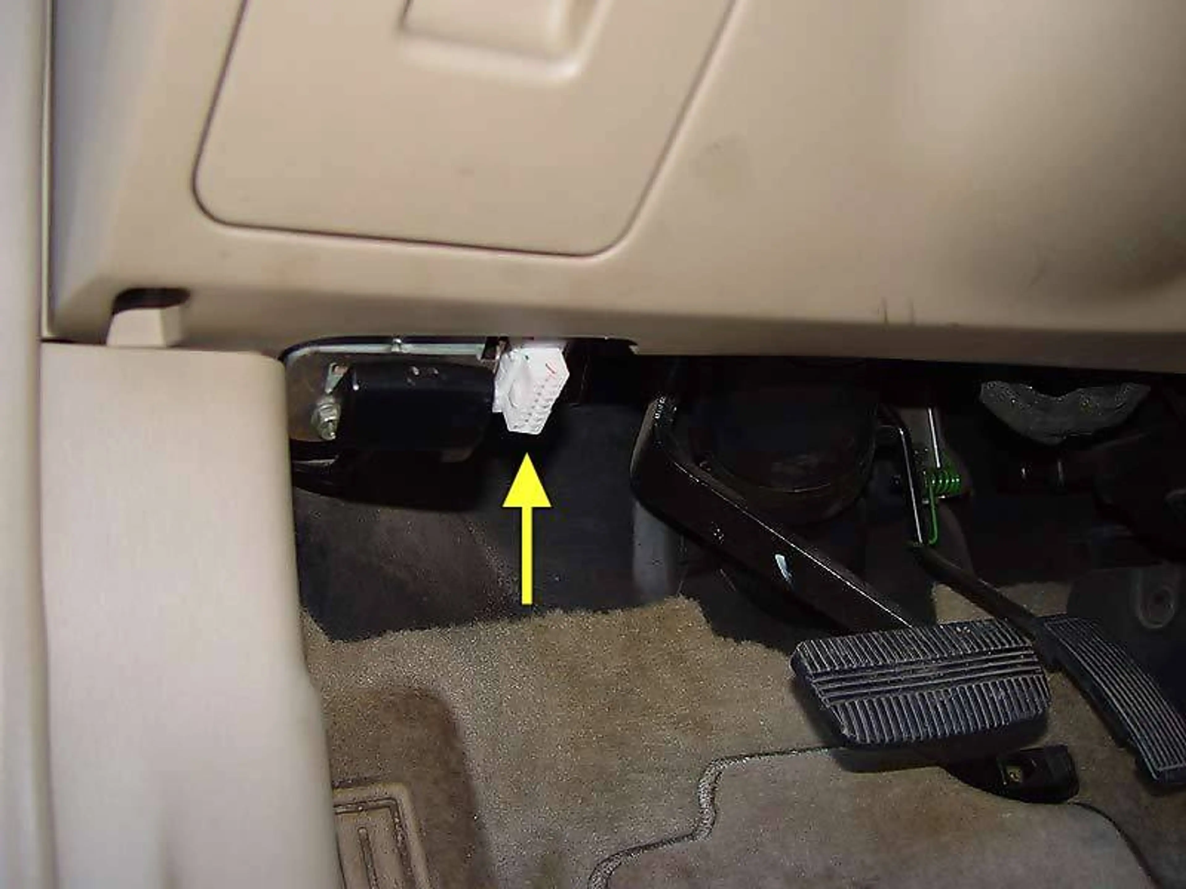 Arrow pointing to the OBD2 device in a car