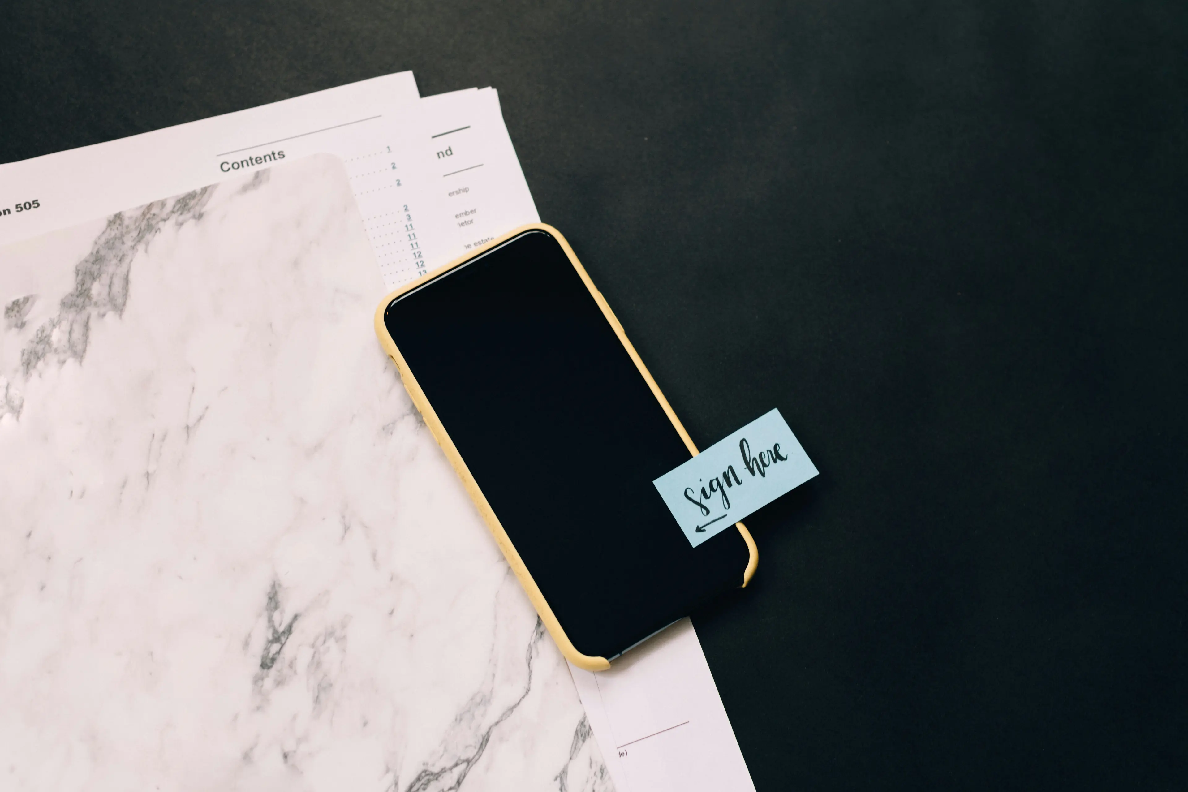 Mobile phone laying on papers. Photo by Kelly Sikkema on Unsplash.