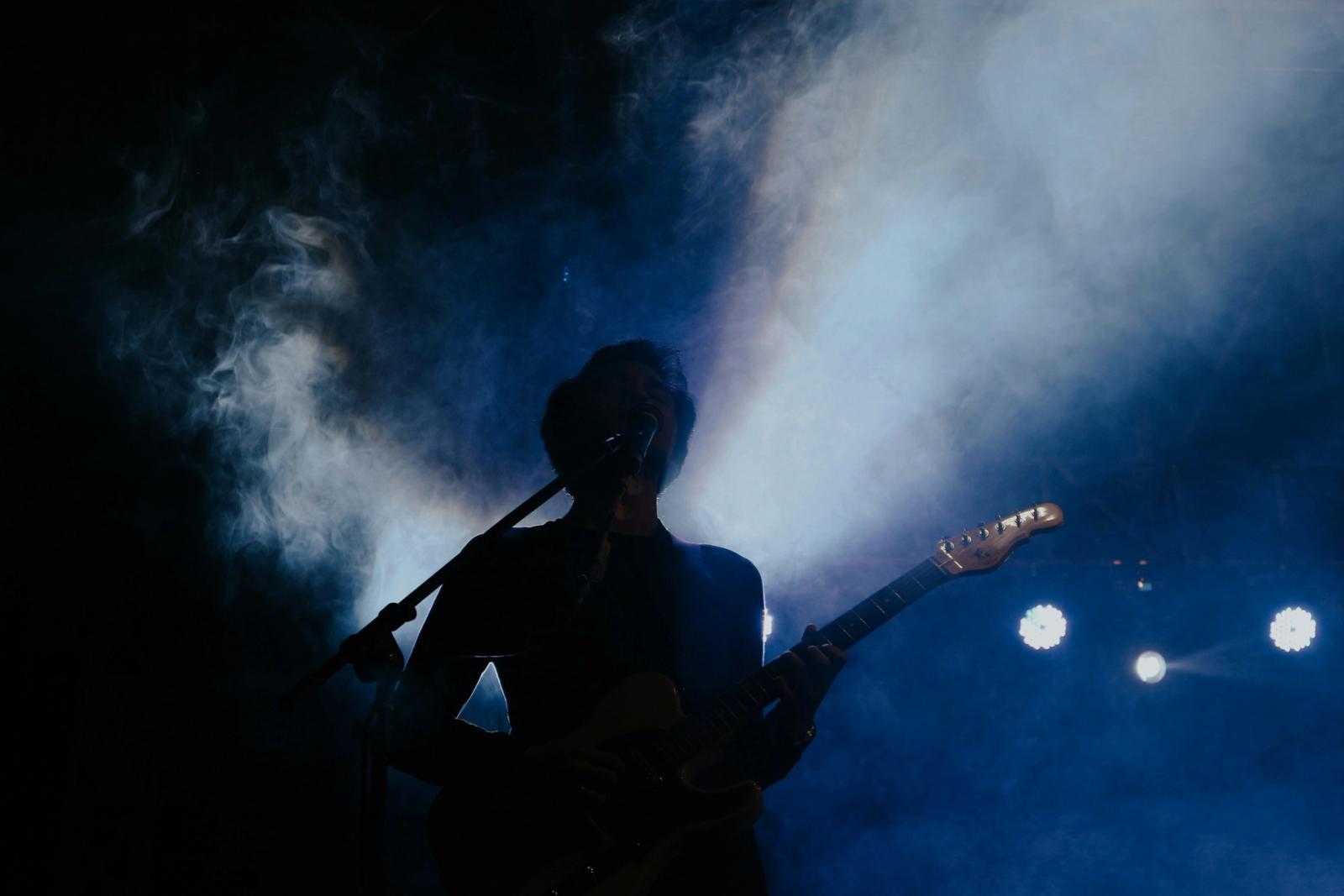 musician holding guitar on stage