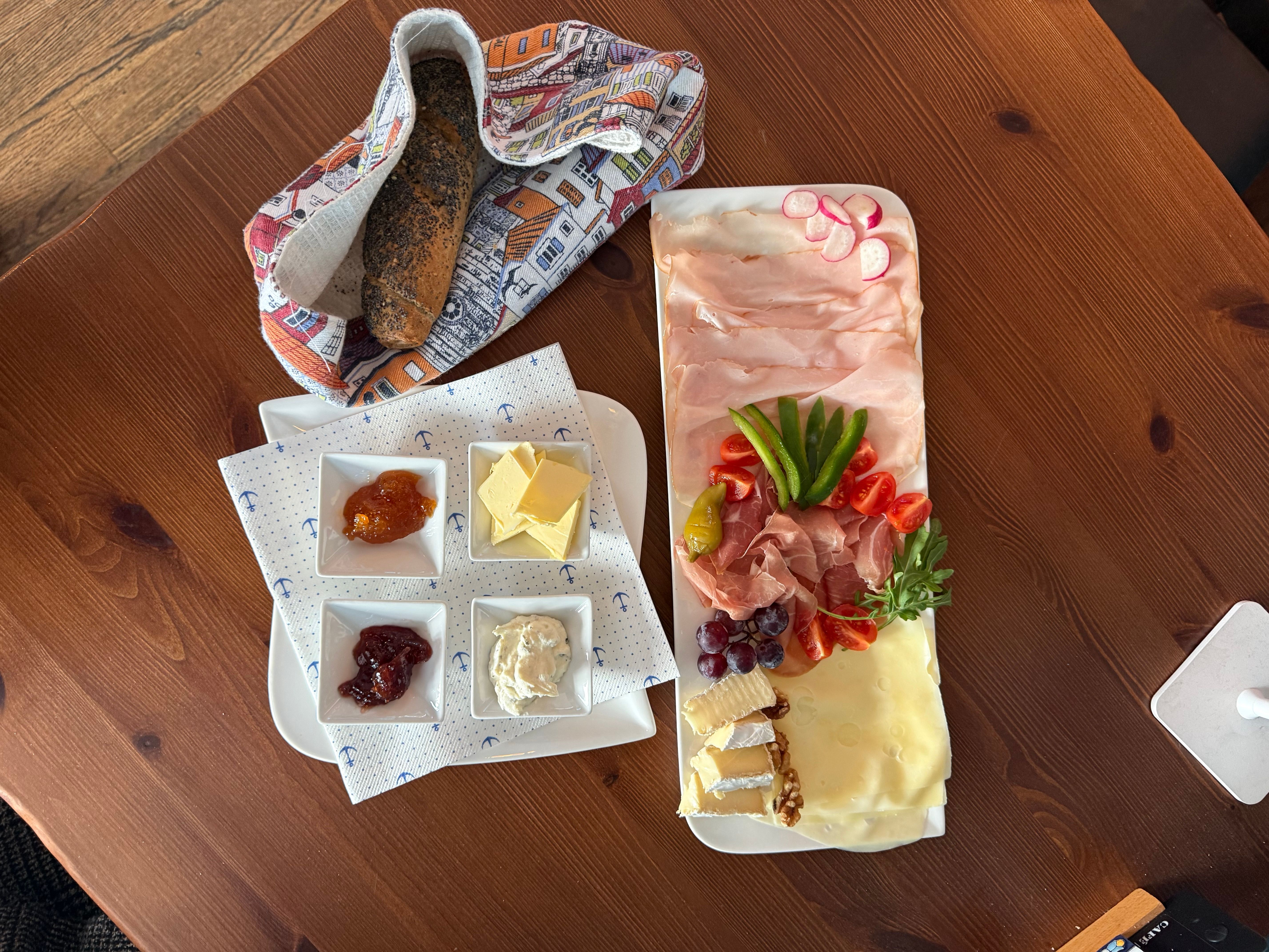 Riverside Frühstück im Porto Gratwein – Aufschnittplatte mit Schinken, Prosciutto, Käse, frischem Gemüse, hausgemachten Aufstrichen und Korngebäck am Holztisch