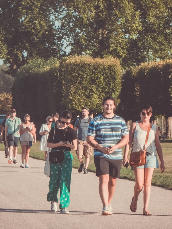 Groupe de festivaliers marchant sur une allée du domaine de Chambord, haies et arbres en arrière-plan