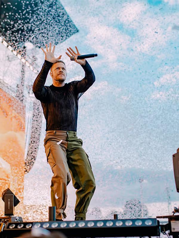 Imagine Dragons sur scène à Chambord, le chanteur micro en main, bras levés sous une pluie de confettis