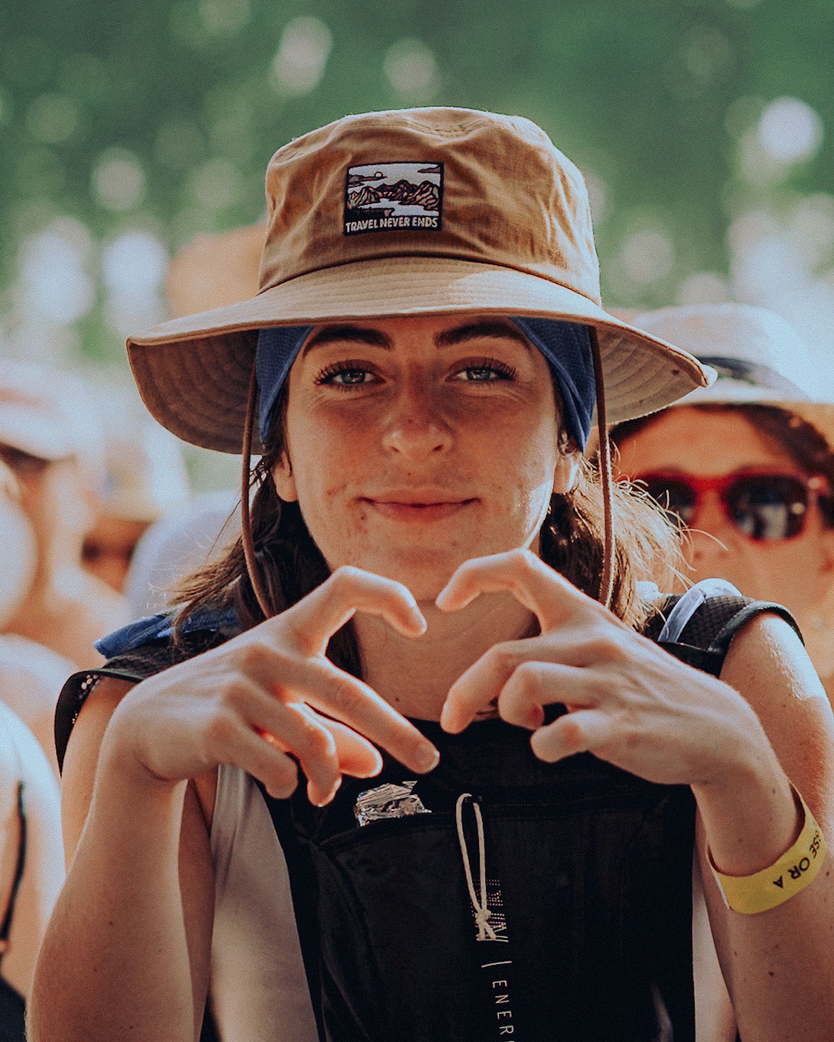 Festivalière au chapeau de brousse formant un cœur avec ses mains au milieu du public