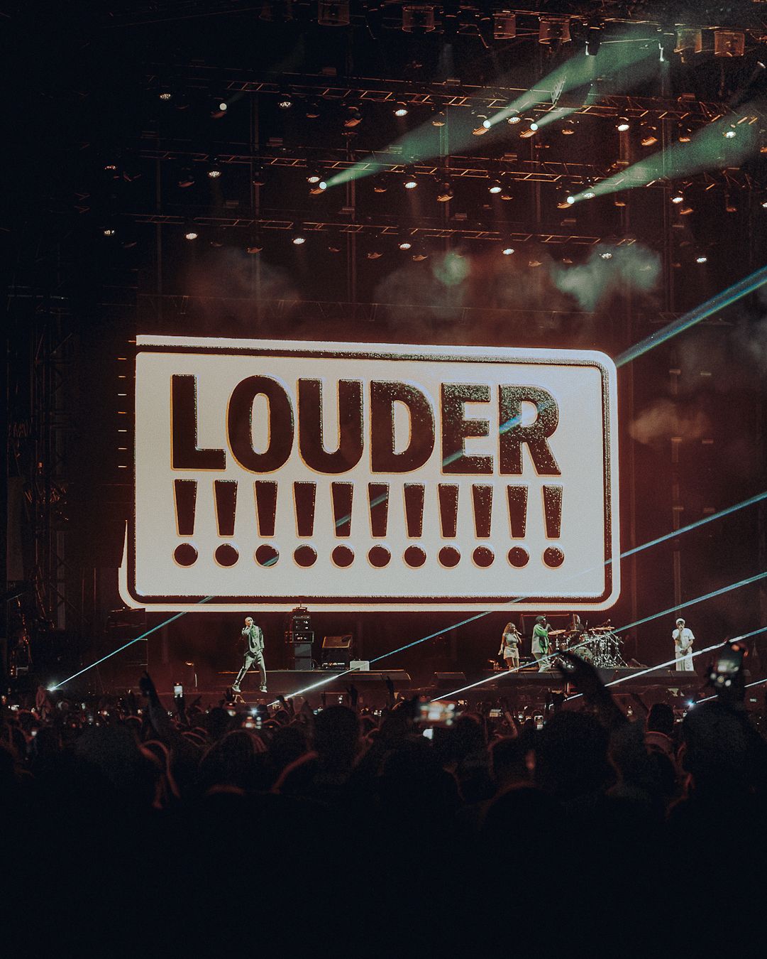 Écran « LOUDER !!! » derrière les musiciens sur la scène de Chambord Live, public au premier plan